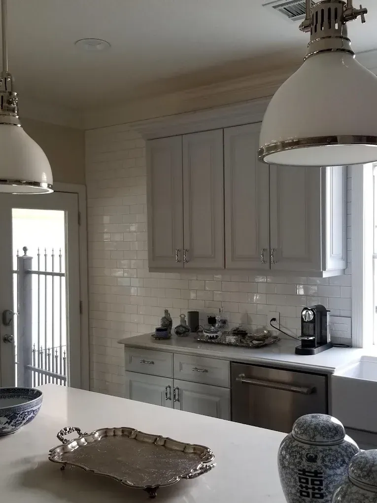 White kitchen with cabinets, subway tile backsplash, stainless steel appliances, and pendant lights.