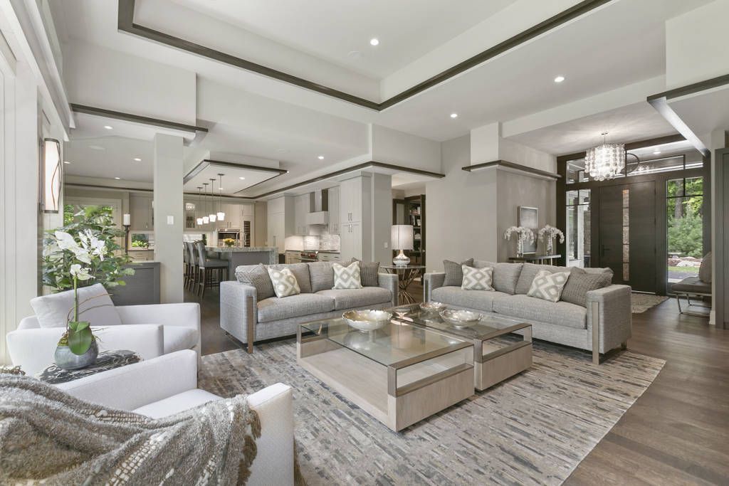 Luxurious living room with gray sofas, glass coffee table, and light-colored rug.