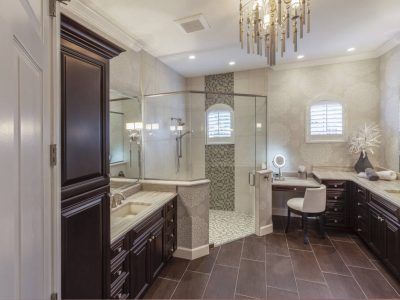 Elegant bathroom with dark brown cabinets, glass shower, and chandelier.