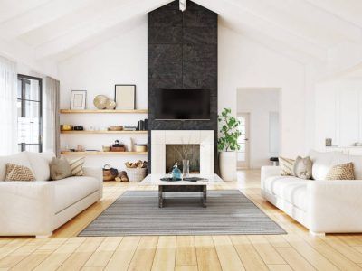 Living room with white sofas, fireplace with TV, and a gray rug on wood floor.