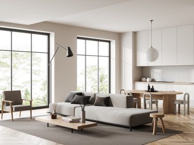 Modern living room with neutral colors, large windows, and open kitchen.