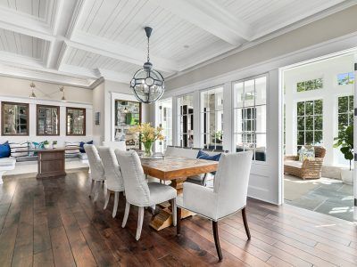 Elegant dining room with wooden table, white chairs, and glass doors opening to patio.