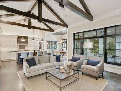 Living room with light gray sofa, two armchairs, and a view into the kitchen and dining area.