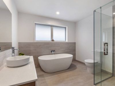 Modern bathroom with a white oval tub, sink, and toilet; glass shower.