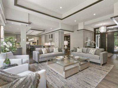 Spacious, modern living room with light gray sofas, coffee tables, and a large area rug.