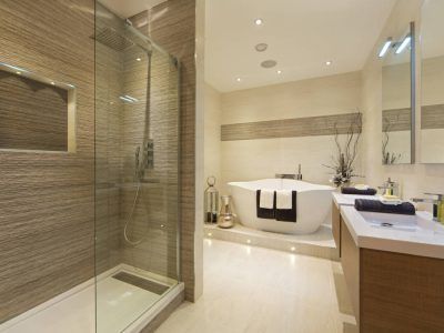 Modern bathroom with glass shower, soaking tub, light wood vanity, and beige tile.