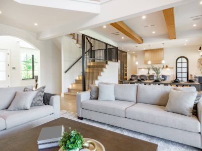 Living room with two gray sofas, staircase, and open kitchen.