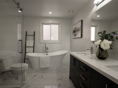White and gray bathroom with a freestanding tub, dark vanity, and a glass shower.
