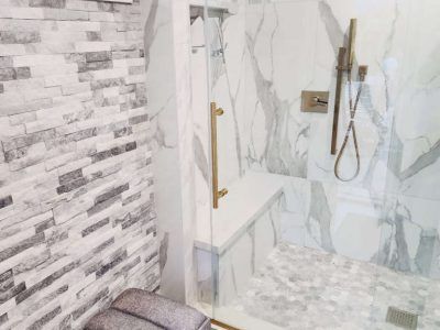Bathroom with marble shower and stone accent wall.