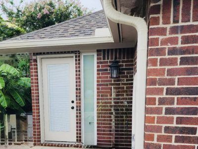 Brick building exterior with door, sidelight, gutter, and black wall lantern.