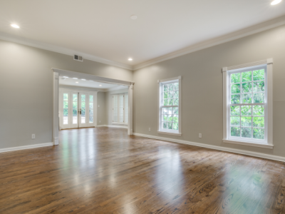 Empty room with wood floors, light gray walls, white trim, and French doors.