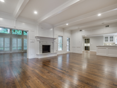 Empty, bright room with hardwood floors, fireplace, and white walls.