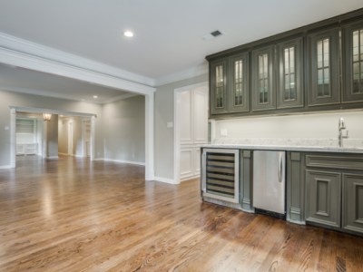 Room with hardwood floors, dark green cabinets, stainless steel appliances, and a pass-through doorway.