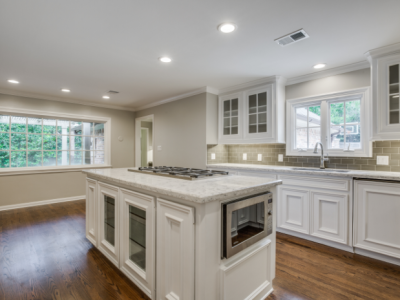 White kitchen with island, built-in microwave, gas cooktop, and hardwood floors.