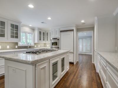White kitchen with island, granite countertops, stainless steel appliances, and wood floor.