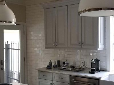 Kitchen with white cabinets, subway tile backsplash, and overhead pendant lights.