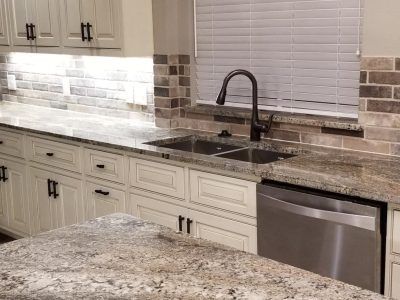Kitchen with white cabinets, granite countertops, and a stainless steel sink and dishwasher.