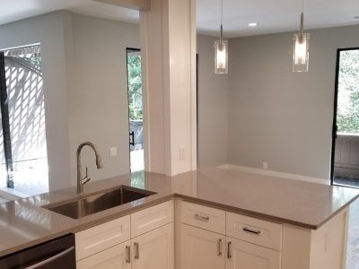 Kitchen with white cabinets, gray countertops, stainless steel sink, and pendant lights.
