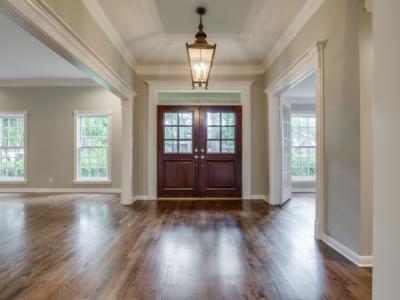 Grand entryway with dark wood double doors, hardwood floors, and a hanging lantern.