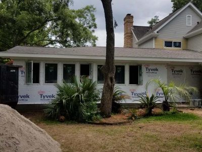 Exterior house addition under construction with Tyvek wrap, windows installed.