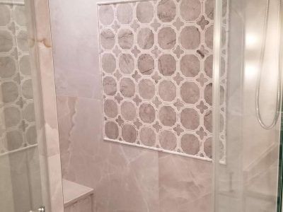 Shower with patterned tile accent, neutral colors, and glass enclosure.