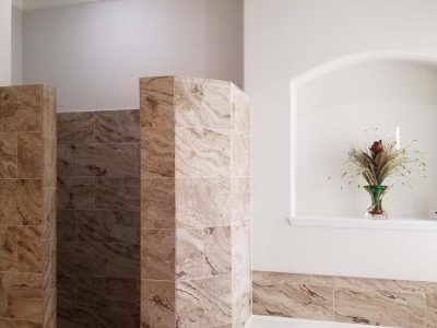 Bathroom interior with tiled shower stall and alcove with vase. Light brown and white color scheme.