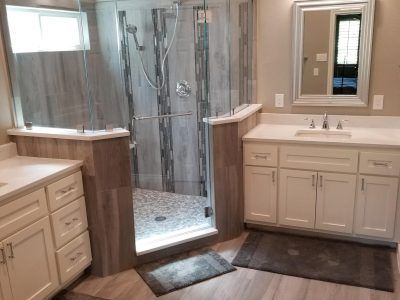 Bathroom with glass shower, white cabinets, and beige walls.