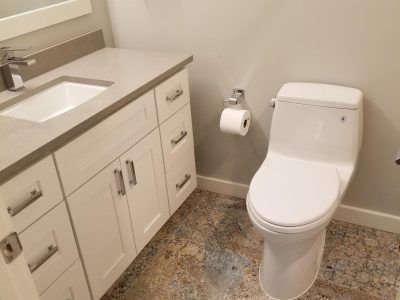 Bathroom with white toilet, vanity, and speckled floor.