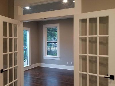 Interior room with French doors, window, and dark wood floor. Painted neutral walls and white trim.