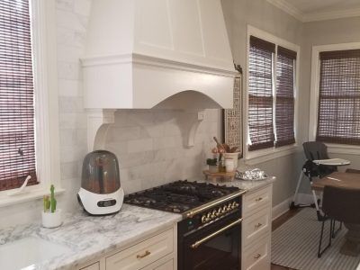 Kitchen with stove, range hood, marble countertops, and woven window shades.