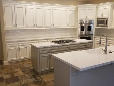 White kitchen with island, cabinets, oven, stovetop, and tile backsplash.