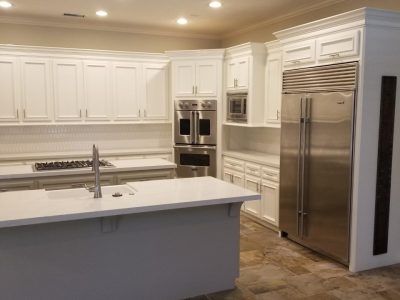 White kitchen with stainless steel refrigerator, island, and cabinetry.