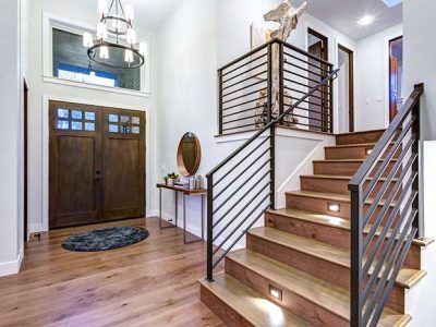 Entryway with wooden door, staircase, and contemporary metal railing.