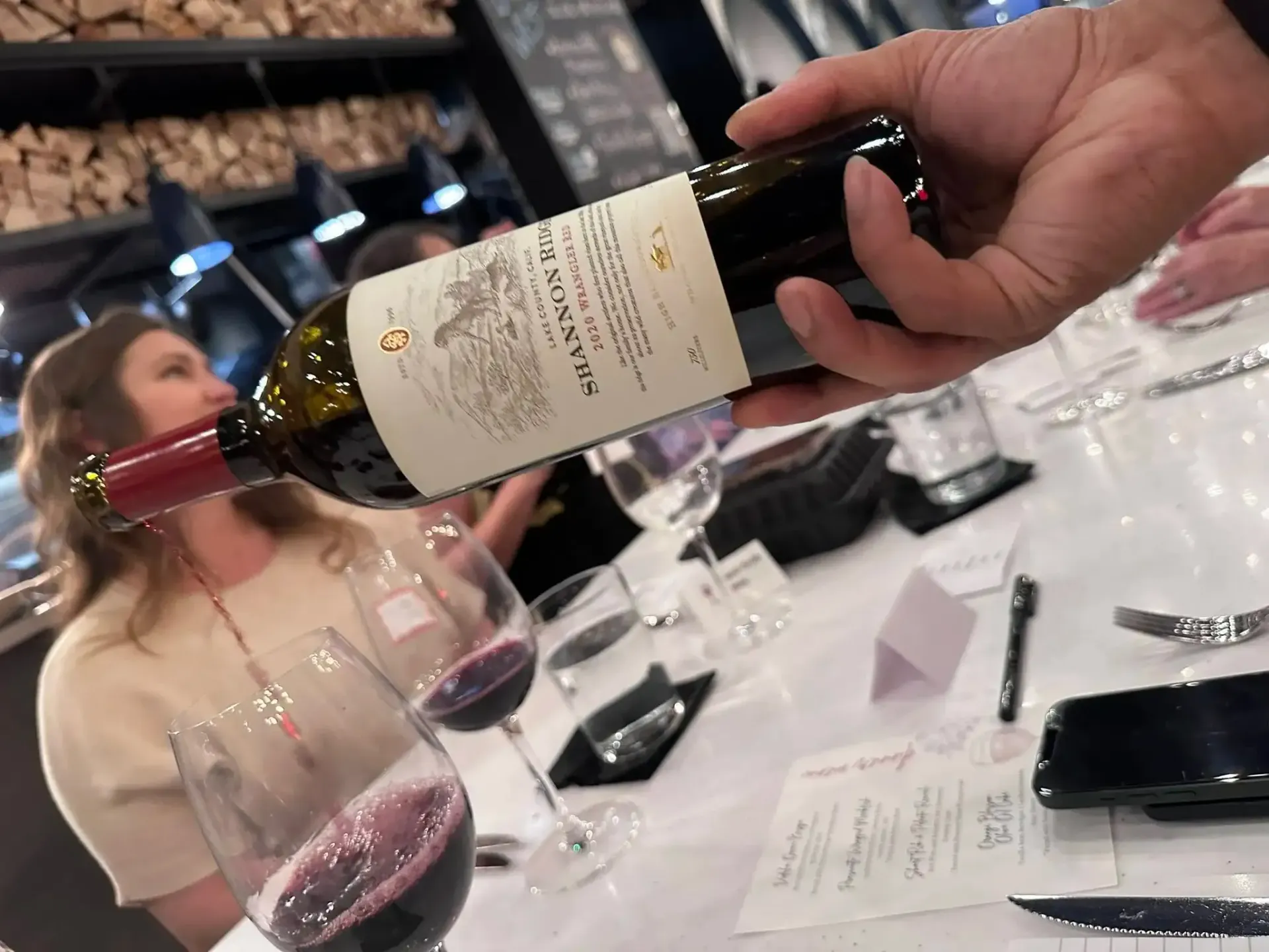 Close-up of champagne glass at a tasting, with place card, and handwritten notes on a table.