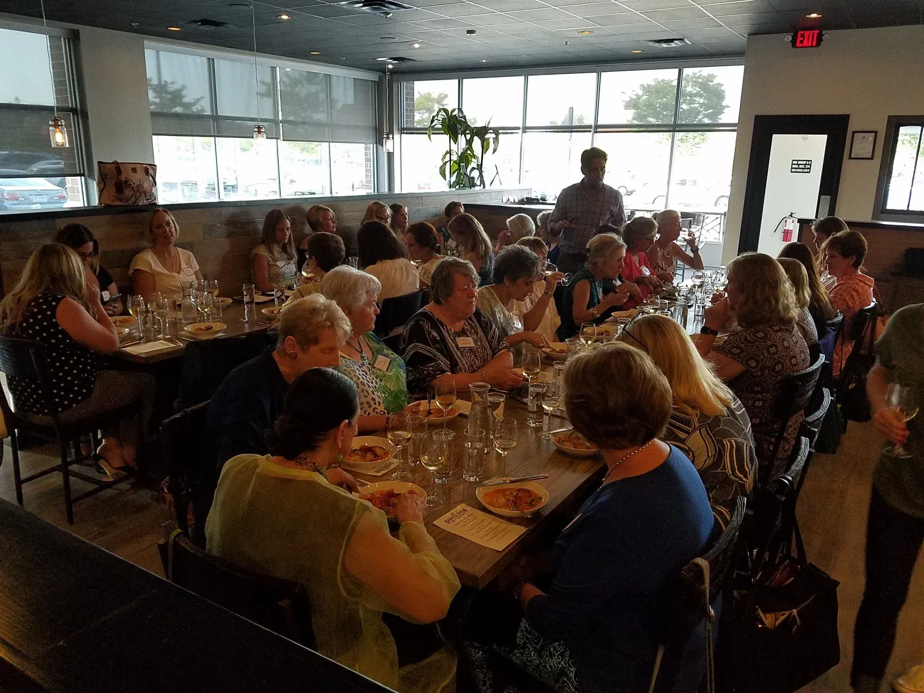 Group of women seated at tables in a restaurant, eating and talking.