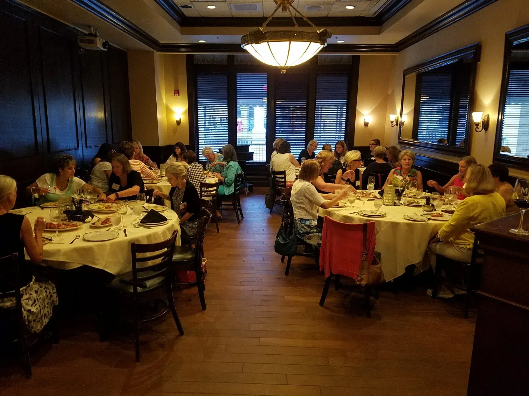 A group of women at round tables in a restaurant dining room, likely enjoying a meal.