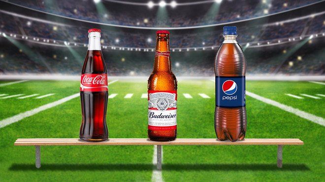 Bottle of coca cola, budwesier, and pepsi on a football field