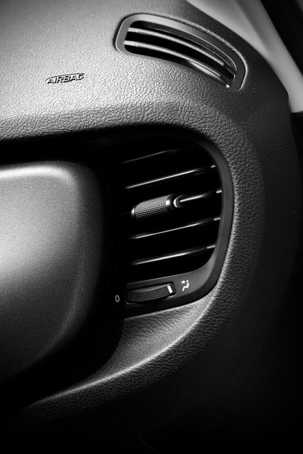 Close-up of a car dashboard air vent and textured black interior trim