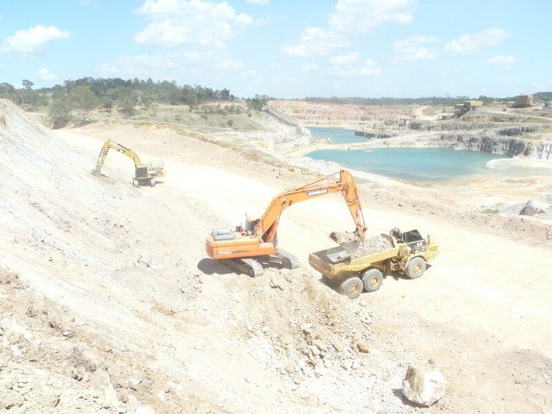 Excavator Loading Rocks on a Truck — Earthmoving & Excavation Services in Rockhampton, QLD