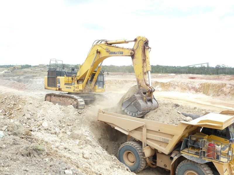 Excavator Loading Rocks on a Truck — Earthmoving & Excavation Services in Rockhampton, QLD