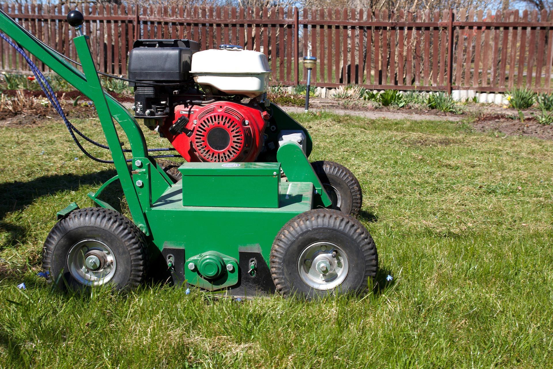 A green lawn mower with a honda engine is sitting on top of a lush green