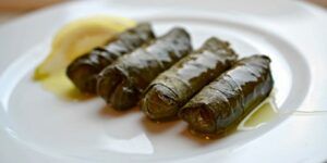 A white plate topped with a row of stuffed grape leaves.