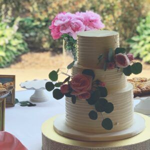 A three tiered wedding cake decorated with pink roses is sitting on a table.