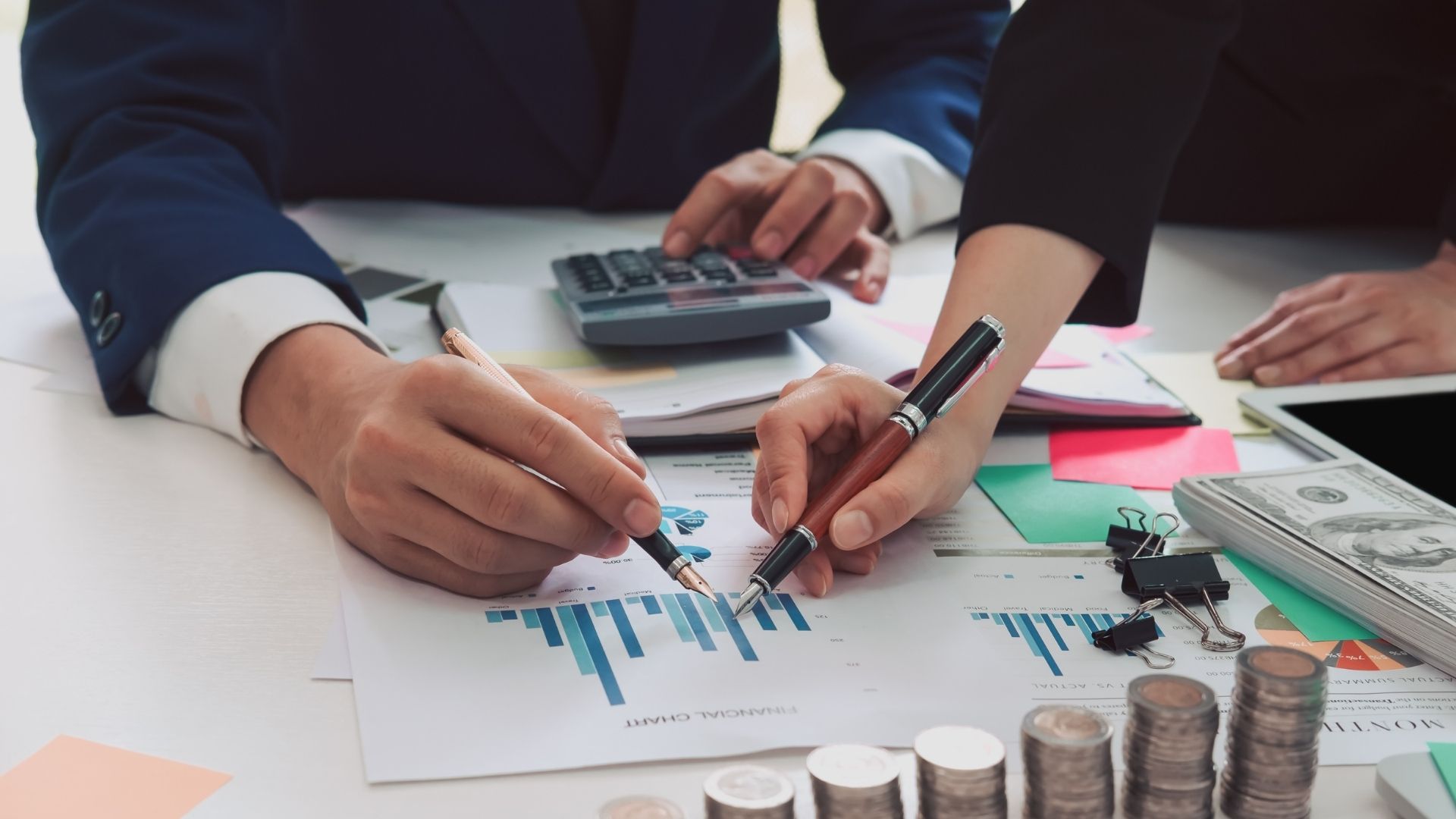 A man is using a calculator while a woman is writing on a piece of paper.