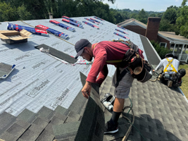 A man is working on the roof of a house.