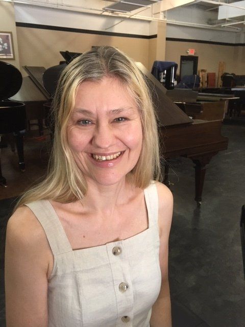 a woman is smiling in front of a piano in a room .