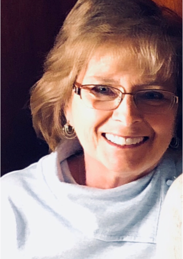 a woman wearing glasses and earrings is smiling for the camera .