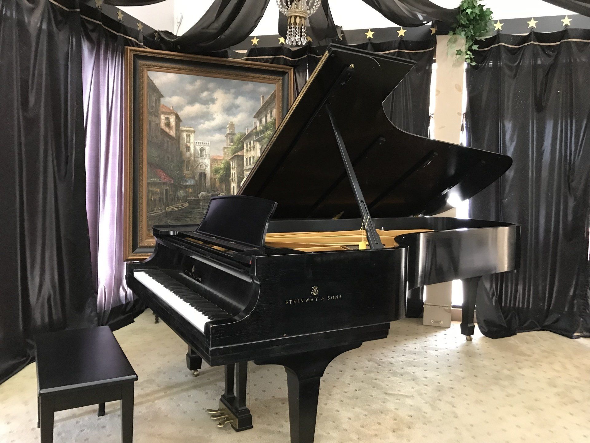 a black grand piano is sitting in a room with a painting on the wall .
