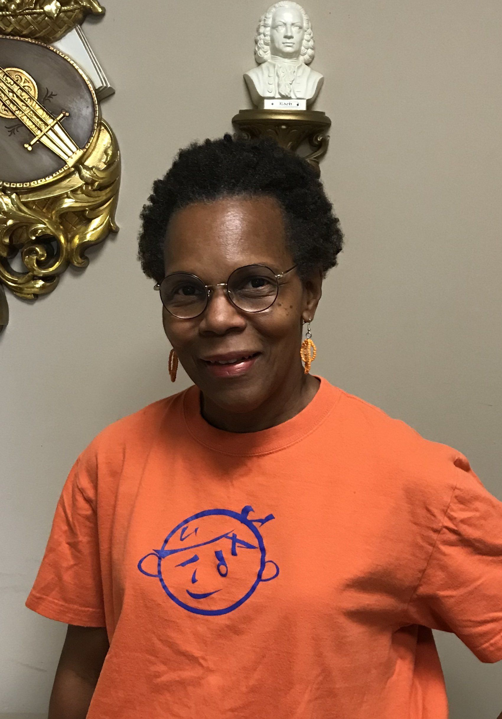 a woman wearing an orange shirt with a drawing of a face on it