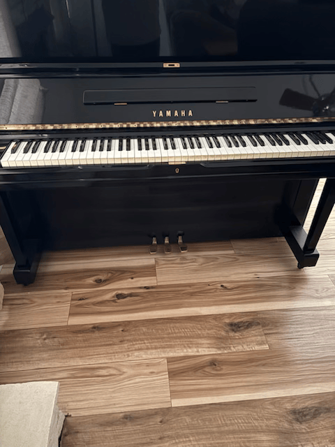 a piano is sitting on a wooden floor next to a bench .